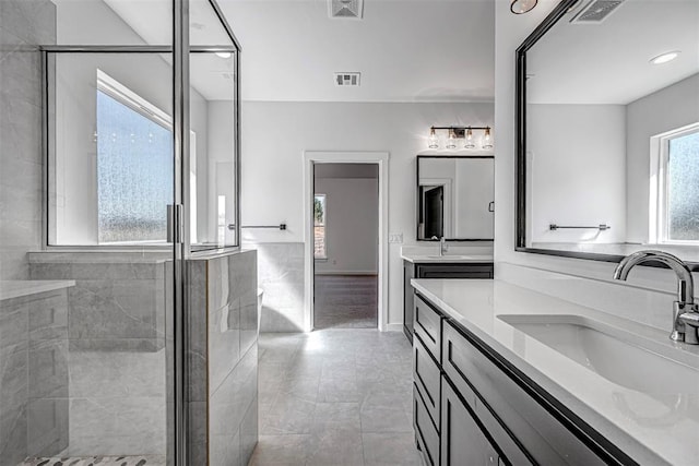 bathroom featuring tile patterned flooring, vanity, and a shower with door