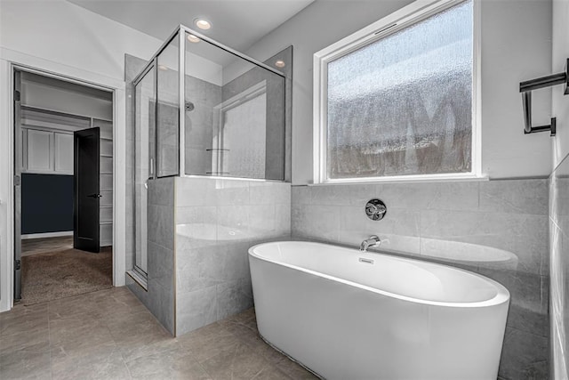 bathroom featuring tile patterned flooring, separate shower and tub, and tile walls