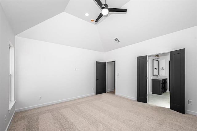 unfurnished bedroom featuring light colored carpet, high vaulted ceiling, ceiling fan, and ensuite bathroom