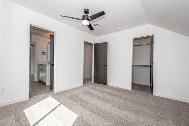 unfurnished bedroom featuring ensuite bath, ceiling fan, a spacious closet, light colored carpet, and lofted ceiling