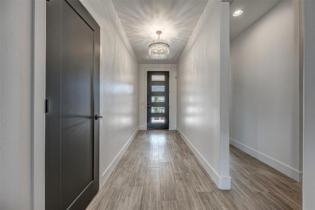 doorway to outside featuring a chandelier and light hardwood / wood-style flooring