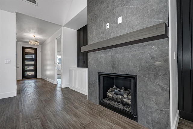 unfurnished living room featuring a premium fireplace, a chandelier, and dark hardwood / wood-style floors