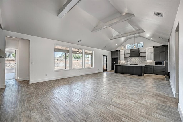 unfurnished living room with vaulted ceiling with beams, ceiling fan, hardwood / wood-style floors, and a healthy amount of sunlight