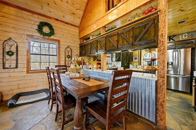 dining area featuring high vaulted ceiling, wooden ceiling, and wood walls