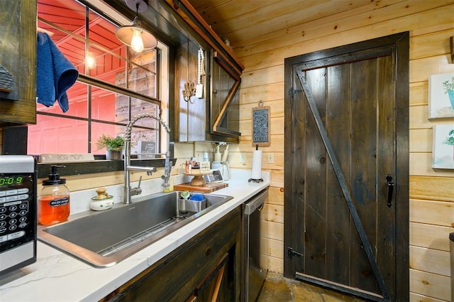 kitchen with stainless steel dishwasher, wooden walls, sink, wooden ceiling, and hanging light fixtures