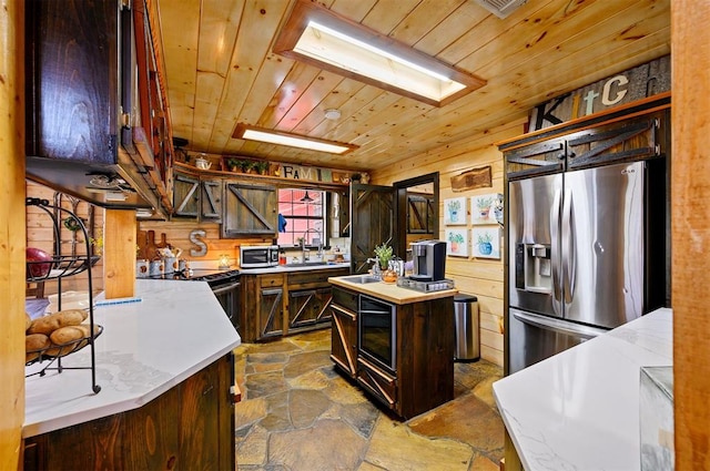 kitchen with dark brown cabinetry, a healthy amount of sunlight, a kitchen island, and stainless steel appliances