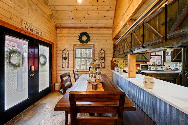 dining area featuring wooden walls, french doors, wooden ceiling, and vaulted ceiling