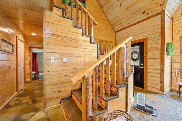 stairway featuring wooden walls, wooden ceiling, and vaulted ceiling