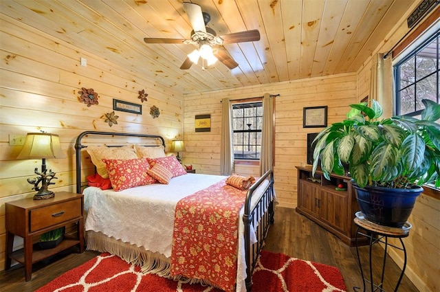 bedroom with ceiling fan, wood ceiling, dark wood-type flooring, and wooden walls