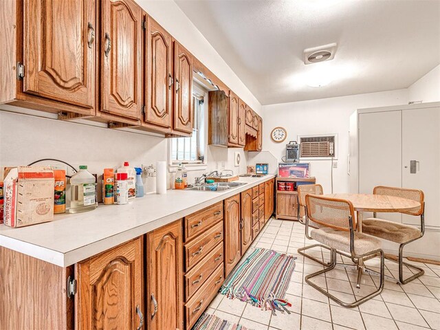 kitchen featuring light tile patterned flooring, sink, and a wall unit AC