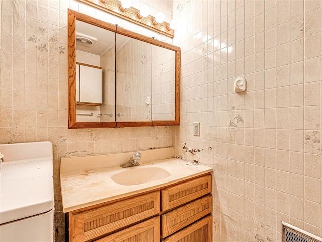 bathroom featuring vanity, tile walls, and toilet