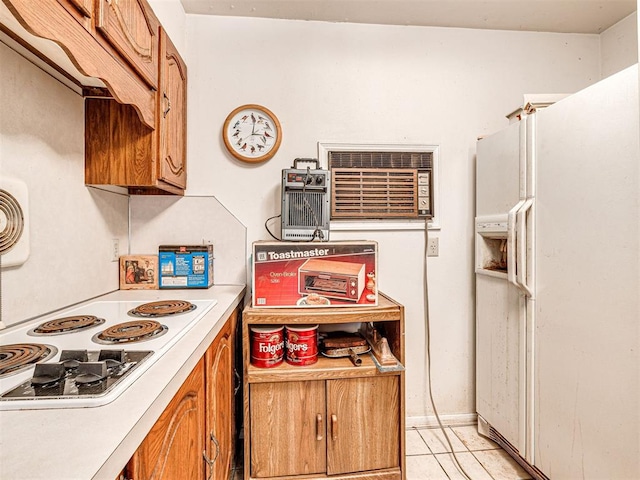 kitchen featuring a wall mounted air conditioner, light tile patterned floors, and white appliances