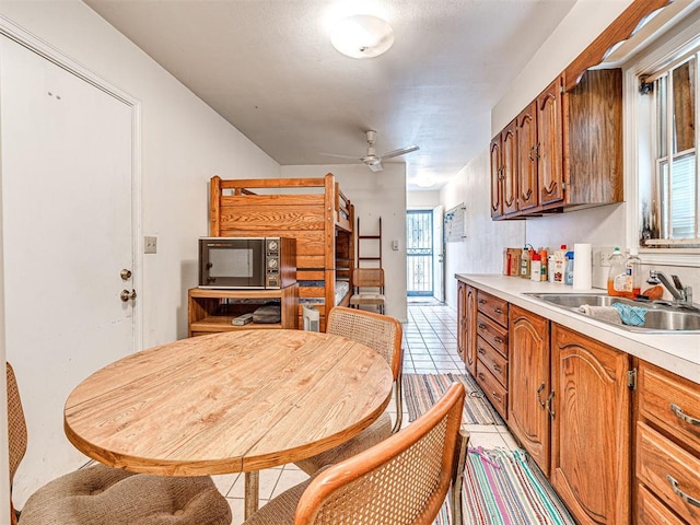 kitchen with light tile patterned floors, ceiling fan, and sink