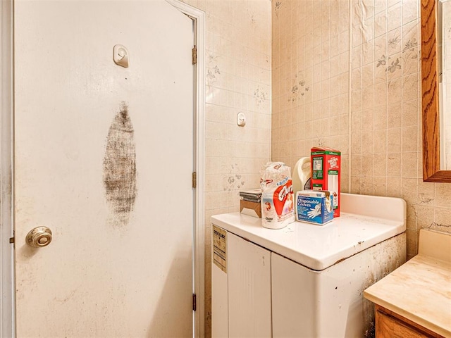 bathroom featuring vanity, washer / clothes dryer, and tile walls