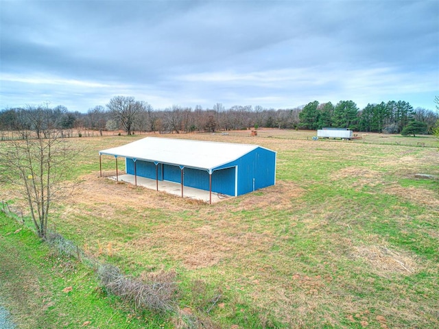 view of swimming pool with an outbuilding, a yard, and a rural view