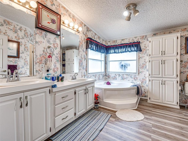 bathroom with a bathing tub, vanity, wood-type flooring, and a textured ceiling