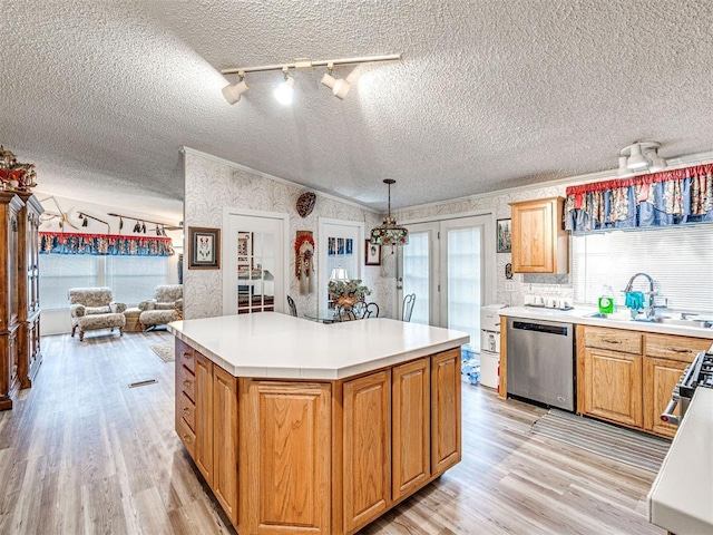 kitchen with a center island, sink, a textured ceiling, decorative light fixtures, and stainless steel appliances