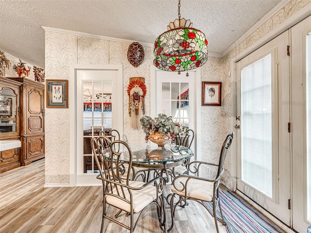 dining space with ornamental molding, light wood-type flooring, and a healthy amount of sunlight