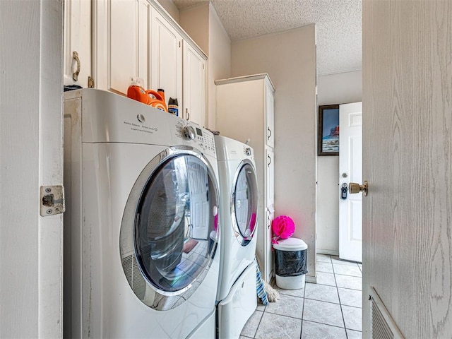 washroom with cabinets, washing machine and dryer, and light tile patterned floors