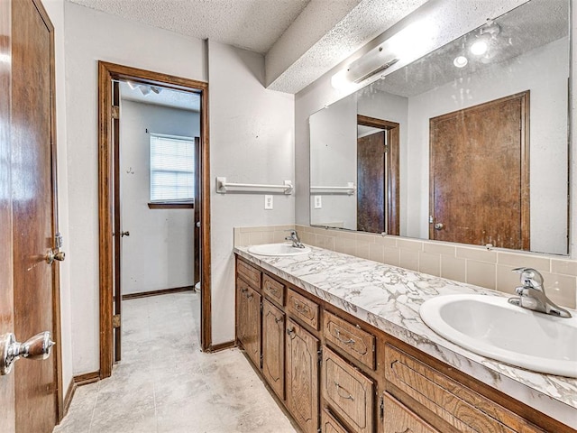 bathroom with vanity, decorative backsplash, and a textured ceiling