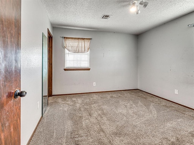 carpeted empty room with a textured ceiling