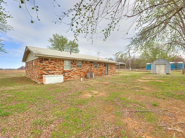 rear view of property with a yard, a storage shed, and central air condition unit