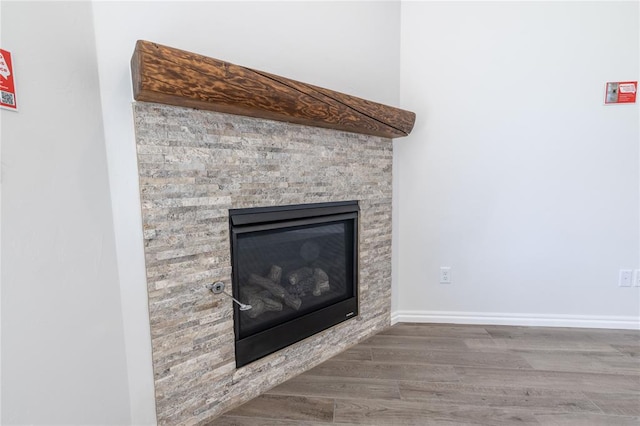 interior details featuring a stone fireplace and wood-type flooring