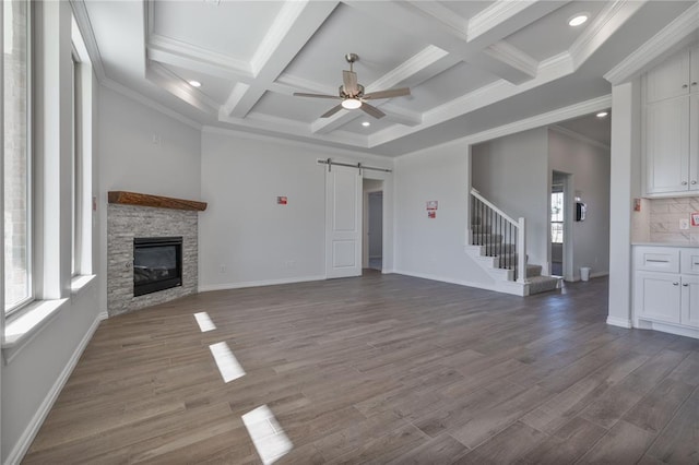 unfurnished living room with hardwood / wood-style flooring, a barn door, ornamental molding, and coffered ceiling