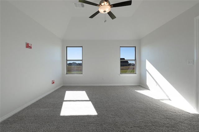 empty room with ceiling fan, plenty of natural light, dark carpet, and vaulted ceiling