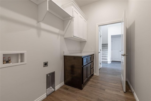 laundry room with hookup for an electric dryer, hookup for a washing machine, light wood-type flooring, and cabinets