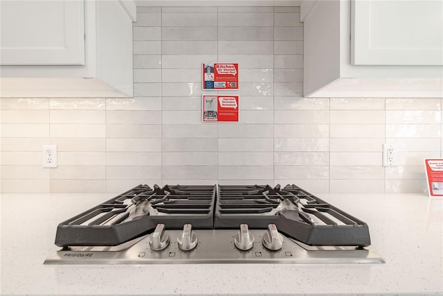 interior details with backsplash, white cabinetry, and stainless steel gas stovetop