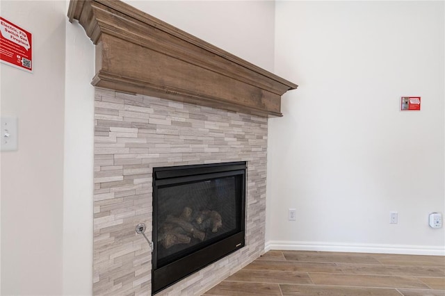 interior details featuring a tiled fireplace and wood-type flooring