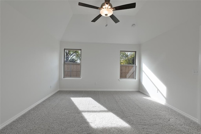 spare room featuring carpet floors, vaulted ceiling, ceiling fan, and a healthy amount of sunlight