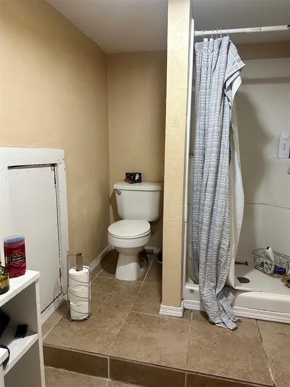 bathroom with tile patterned floors, toilet, and walk in shower