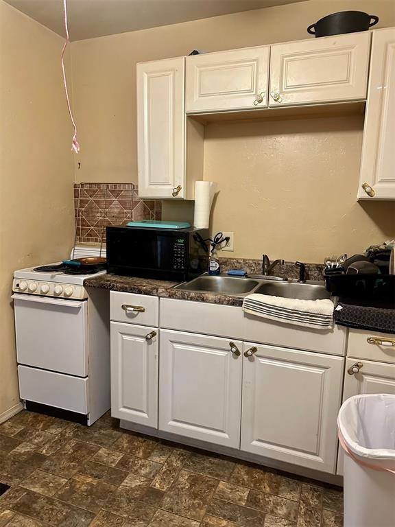 kitchen with backsplash, sink, white cabinets, and white range