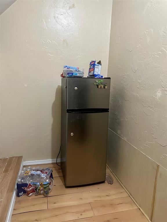 interior details featuring stainless steel fridge and hardwood / wood-style flooring