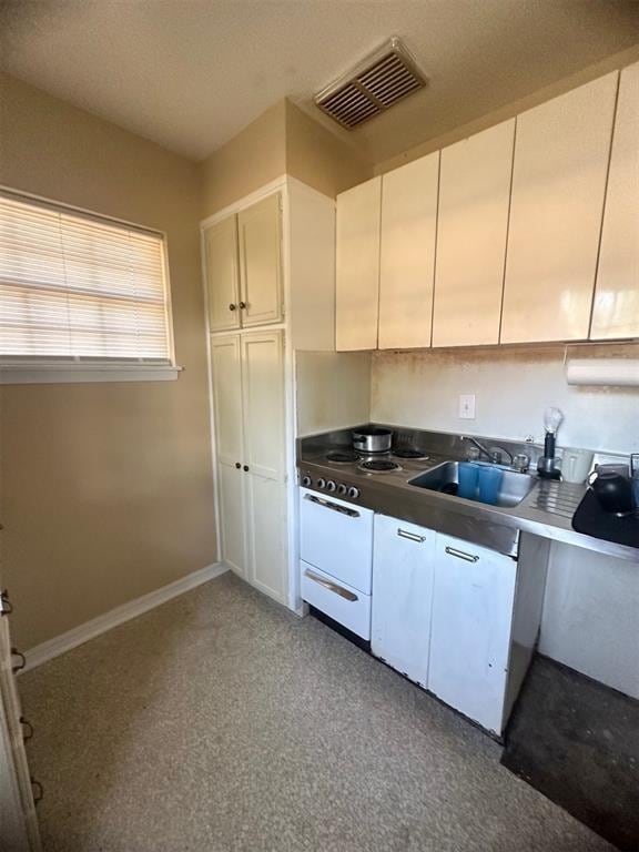 kitchen with white range oven, sink, and white cabinets