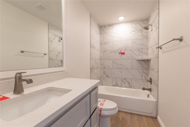 full bathroom with vanity, hardwood / wood-style flooring, toilet, and tiled shower / bath