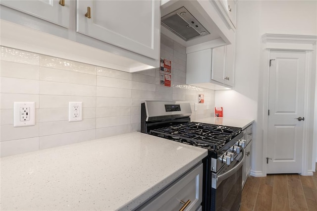 kitchen featuring decorative backsplash, light stone counters, custom range hood, light hardwood / wood-style flooring, and stainless steel gas stove