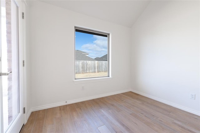 spare room with lofted ceiling and light wood-type flooring