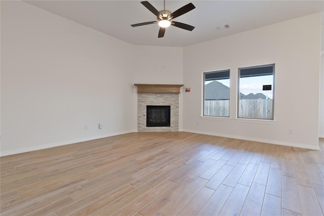 unfurnished living room featuring a tile fireplace, ceiling fan, and light hardwood / wood-style flooring