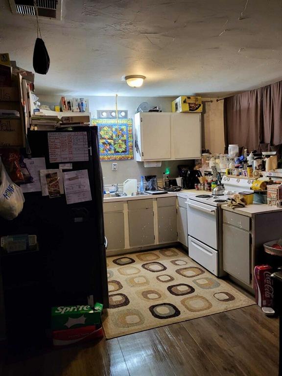 kitchen with black refrigerator, light wood-type flooring, sink, white cabinets, and white range with electric cooktop