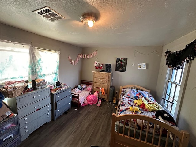 bedroom with multiple windows, dark wood-type flooring, and a textured ceiling