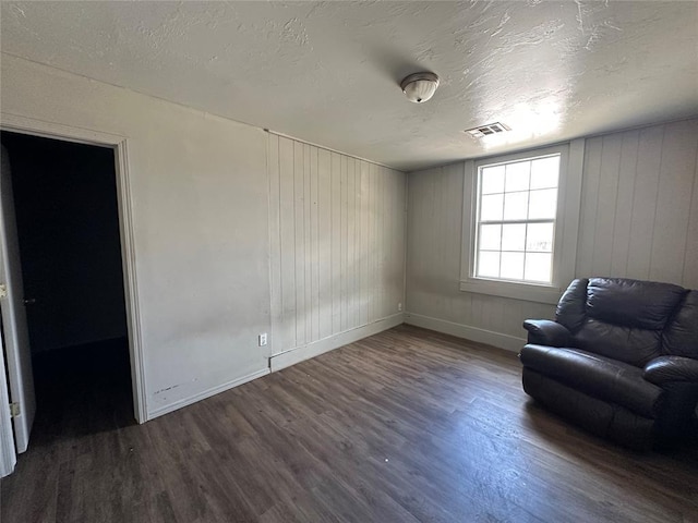 unfurnished room featuring a textured ceiling, wood finished floors, visible vents, and baseboards