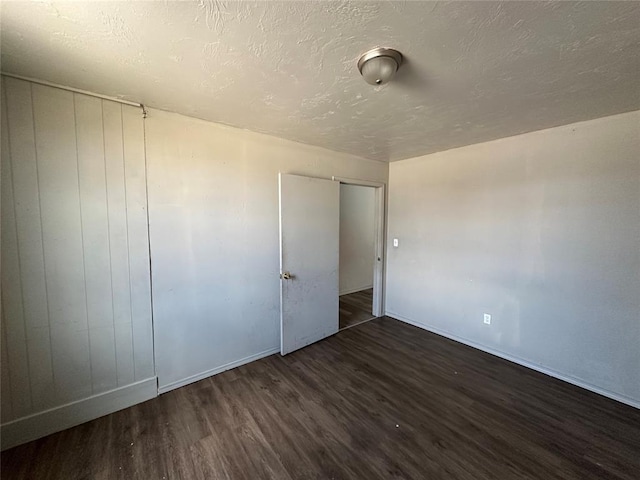 unfurnished bedroom featuring a textured ceiling, baseboards, and wood finished floors