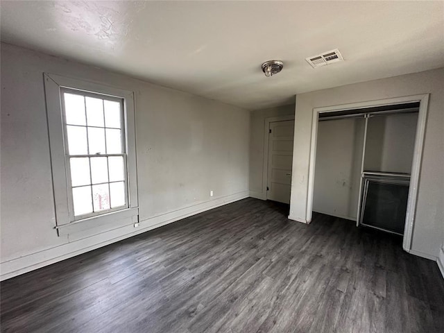 unfurnished bedroom featuring dark wood-style floors, baseboards, and visible vents