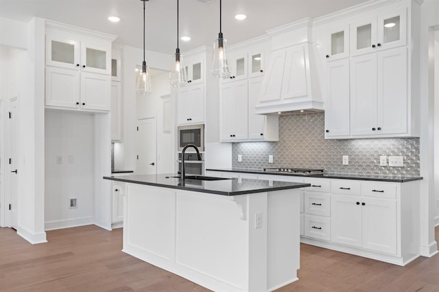 kitchen featuring white cabinetry, a kitchen island with sink, sink, and custom exhaust hood