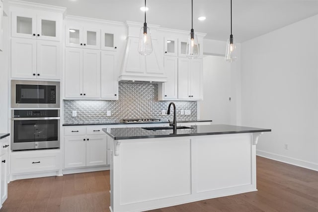 kitchen with dark hardwood / wood-style floors, white cabinetry, stainless steel appliances, and a kitchen island with sink