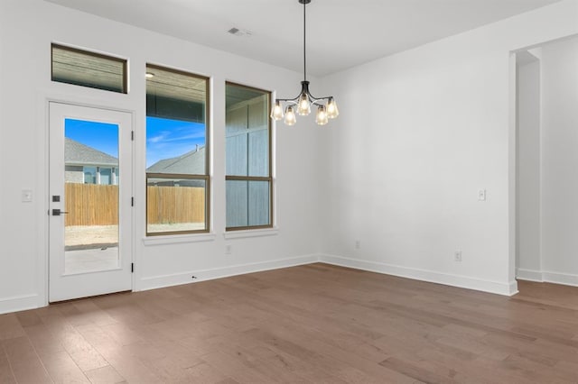 spare room with hardwood / wood-style floors and an inviting chandelier