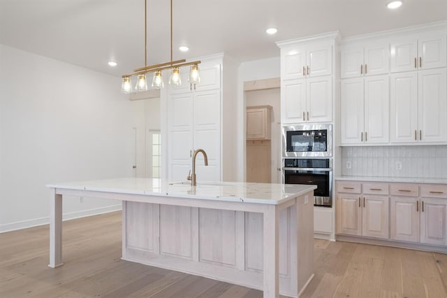 kitchen with white cabinetry, a kitchen island with sink, light hardwood / wood-style flooring, and stainless steel appliances